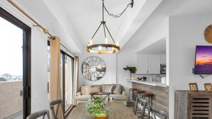 A modern dining area with a wooden table, chairs, a chandelier, and a large mirror.