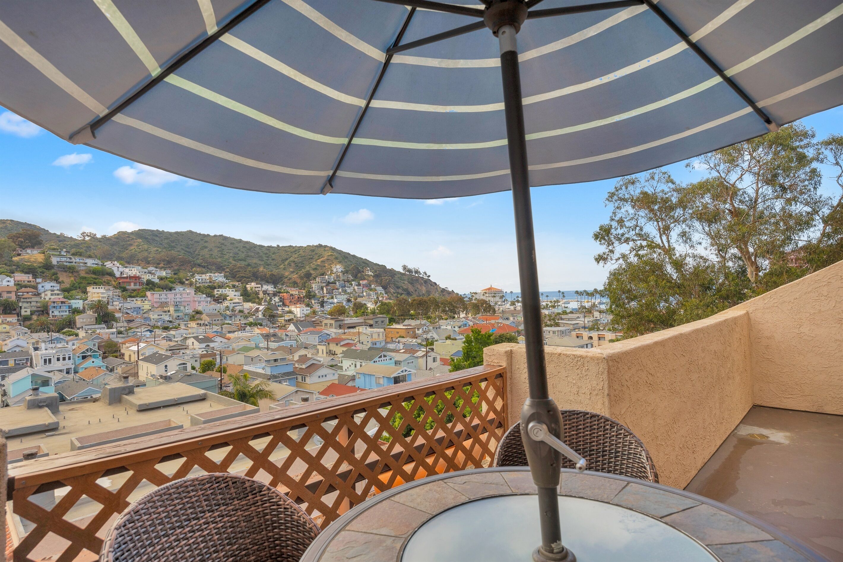 Un balcón con vistas a un pueblo, una sombrilla y muebles de mimbre.