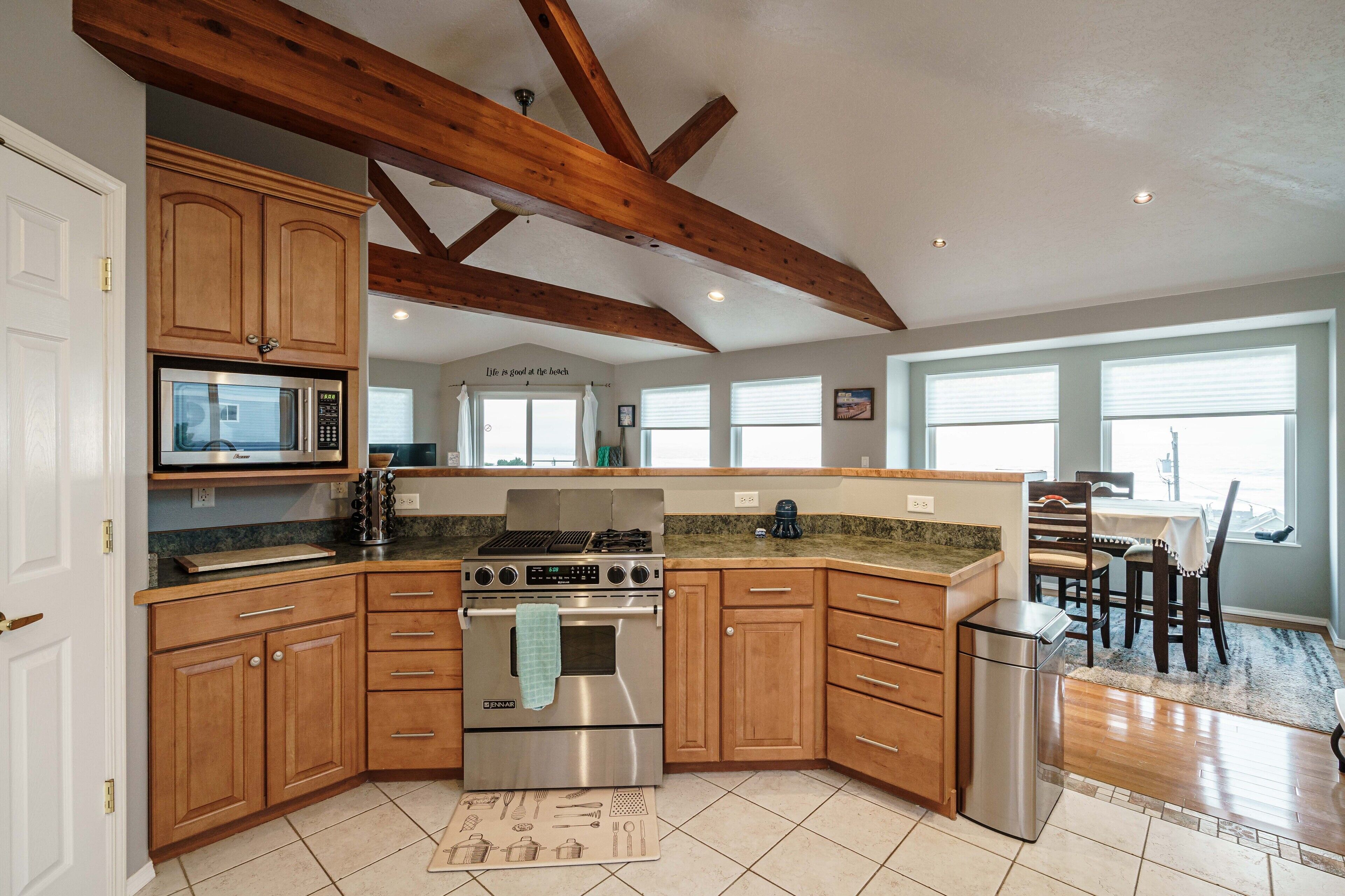 Une cuisine dotée d’armoires en bois, d’un four à micro-ondes encastré, d’un four Jenn-Air et d’un réfrigérateur en acier inoxydable.