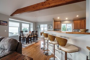 Una cocina moderna con armarios de madera, una barra con taburetes y un comedor con mesa y sillas.