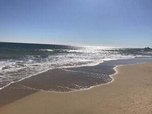 A beach with waves gently lapping onto the shore under a clear sky. - Beach Cottage 1 Mile From Weekapaug & Misquamicut (Westerly)