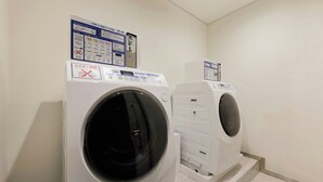 A laundry room with two front-loading washing machines and a control panel with instructions. - Four Points Flex by Sheraton Morioka (Morioka)