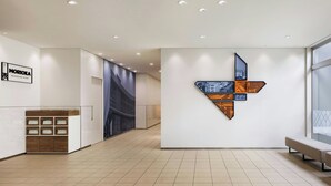 A modern hotel lobby with a reception desk, a wall-mounted artwork, and a bench. - Four Points Flex by Sheraton Morioka (Morioka)