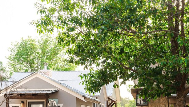 A rustic building with a stone facade, a black door, and a sign indicating a restaurant. - Romantic Fredericksburg Cottage w/ Hot Tub (Fredericksburg)