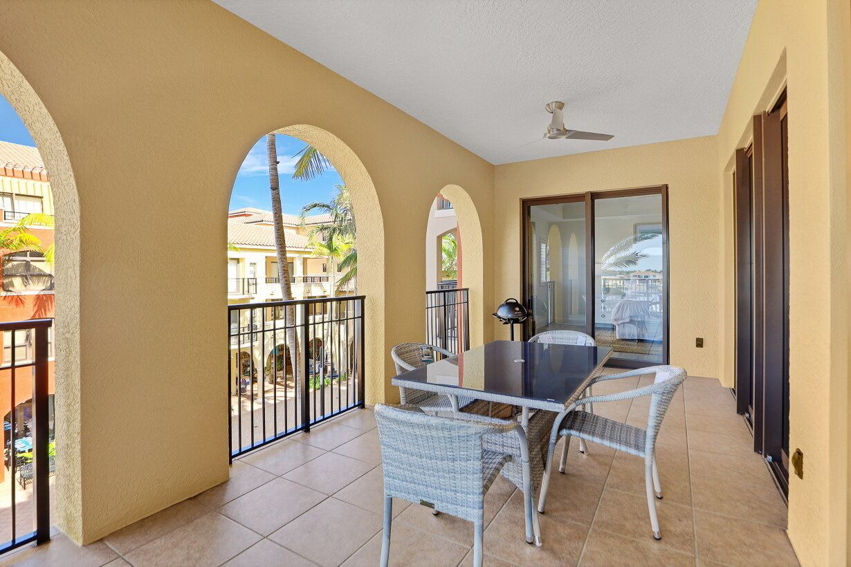 A balcony with a table and chairs, a ceiling fan, and a view of the street.