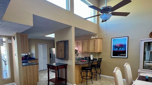 A spacious kitchen with high ceilings, a dining area with a table and chairs, and a ceiling fan. - Sandia Heights #1 rental (ALBUQUERQUE)