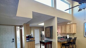 A spacious kitchen with high ceilings, a dining area with chairs, and a ceiling fan. - Sandia Heights #1 rental (ALBUQUERQUE)