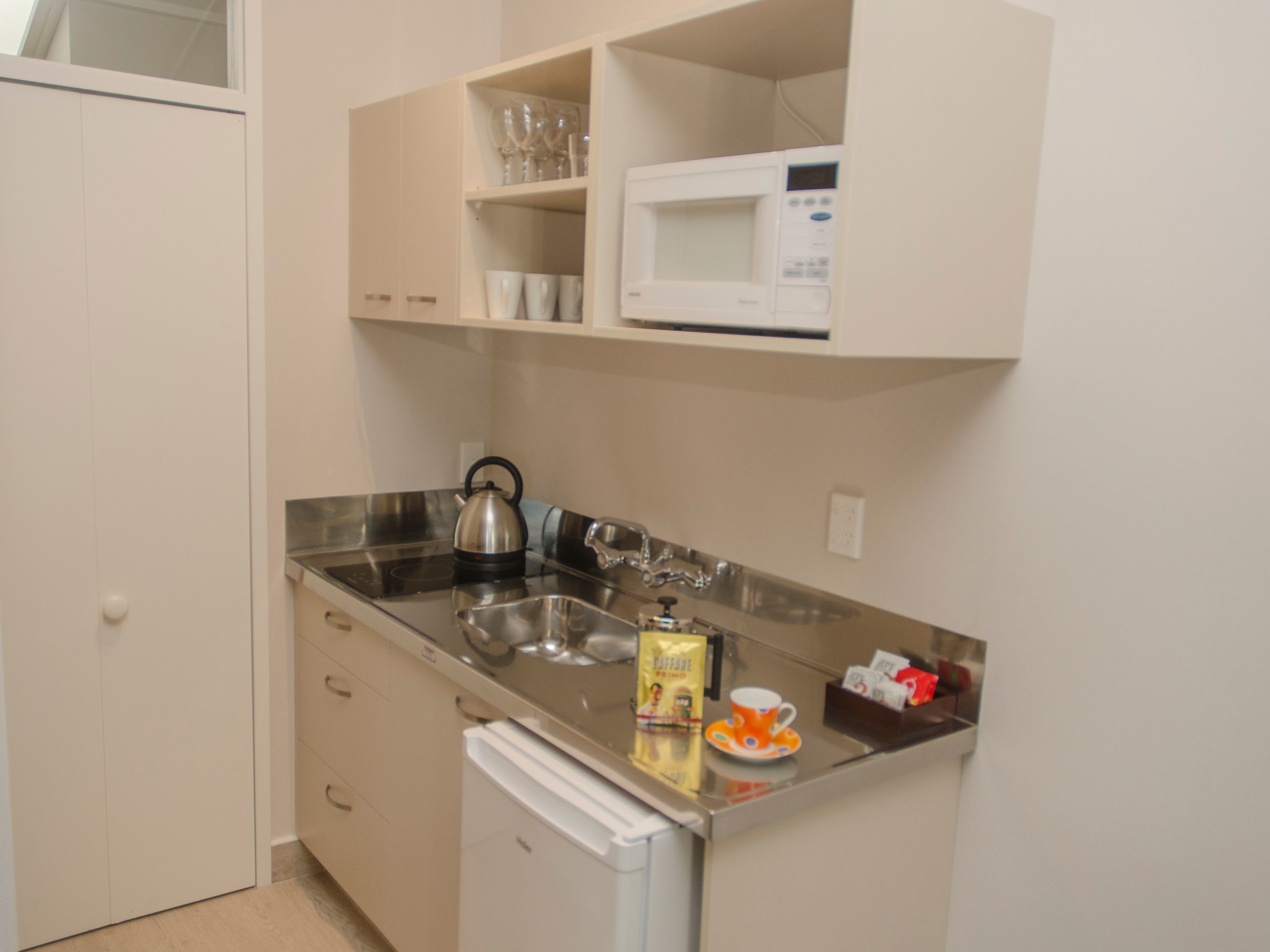 A compact kitchen with a microwave, kettle, and coffee maker.