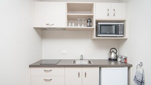 A compact kitchenette with a microwave, kettle, and a small refrigerator. - Cedar Lodge Motel (Timaru)