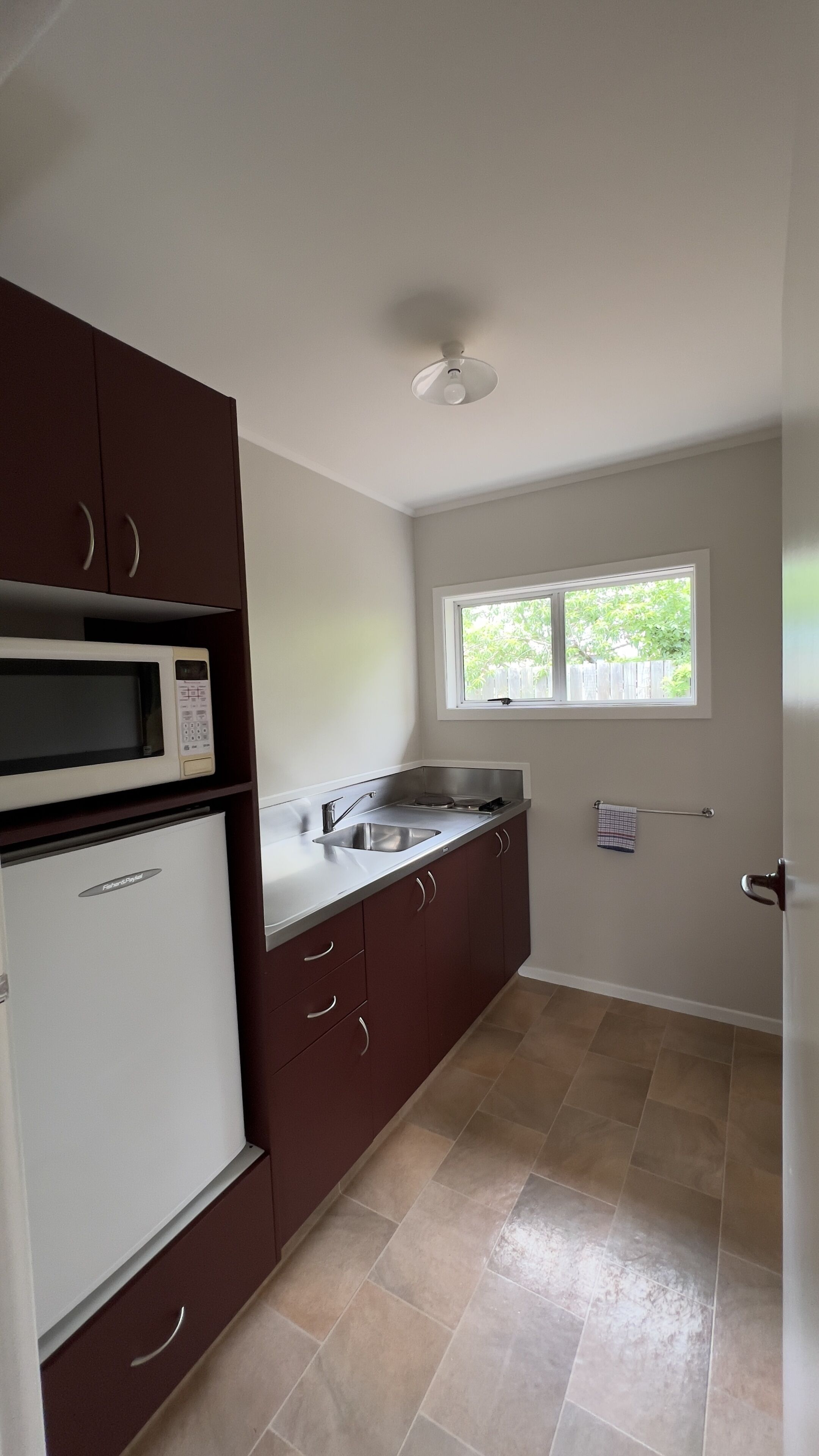 A kitchen with a microwave, refrigerator, sink, and cabinets.