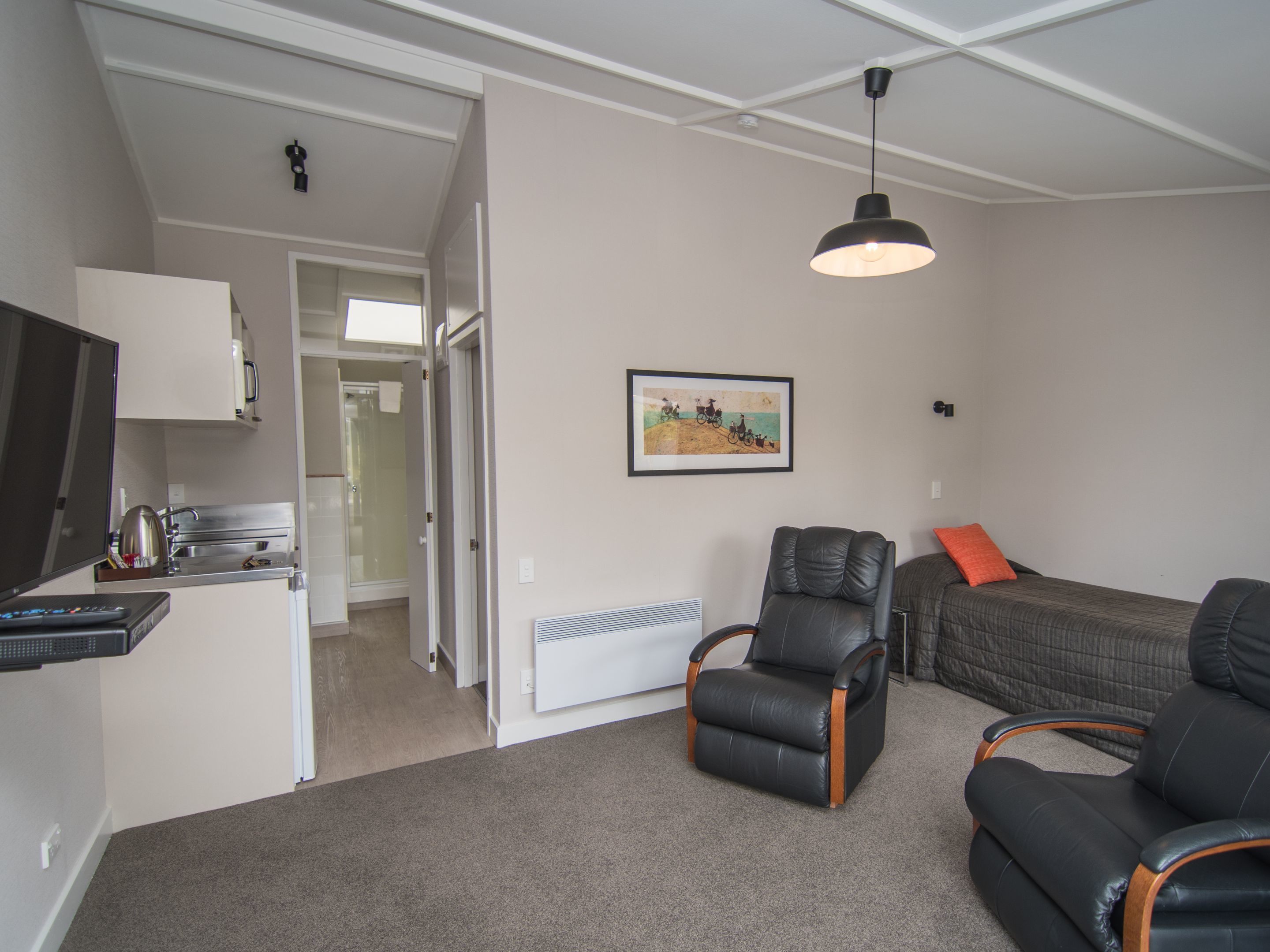 A compact living space with a kitchenette, a dining area, a sofa, and a chair.
