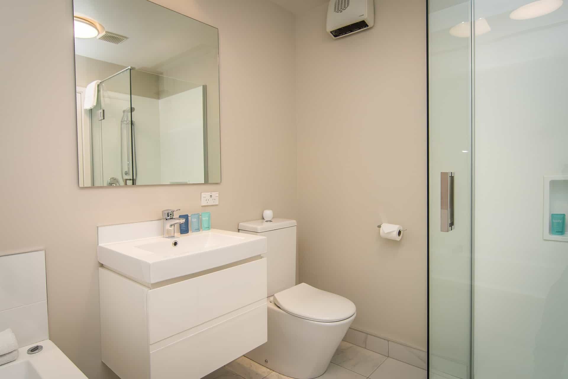 Ein modernes Badezimmer mit Waschbecken, Spiegel und Toilette.