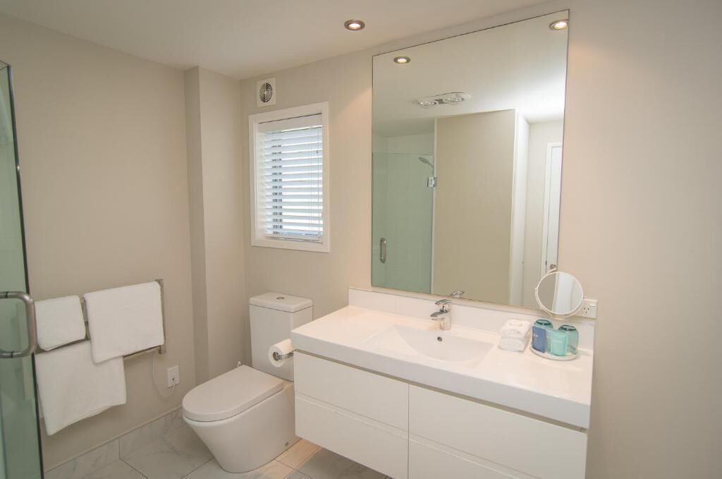 Une salle de bain avec des toilettes, un lavabo et un miroir.