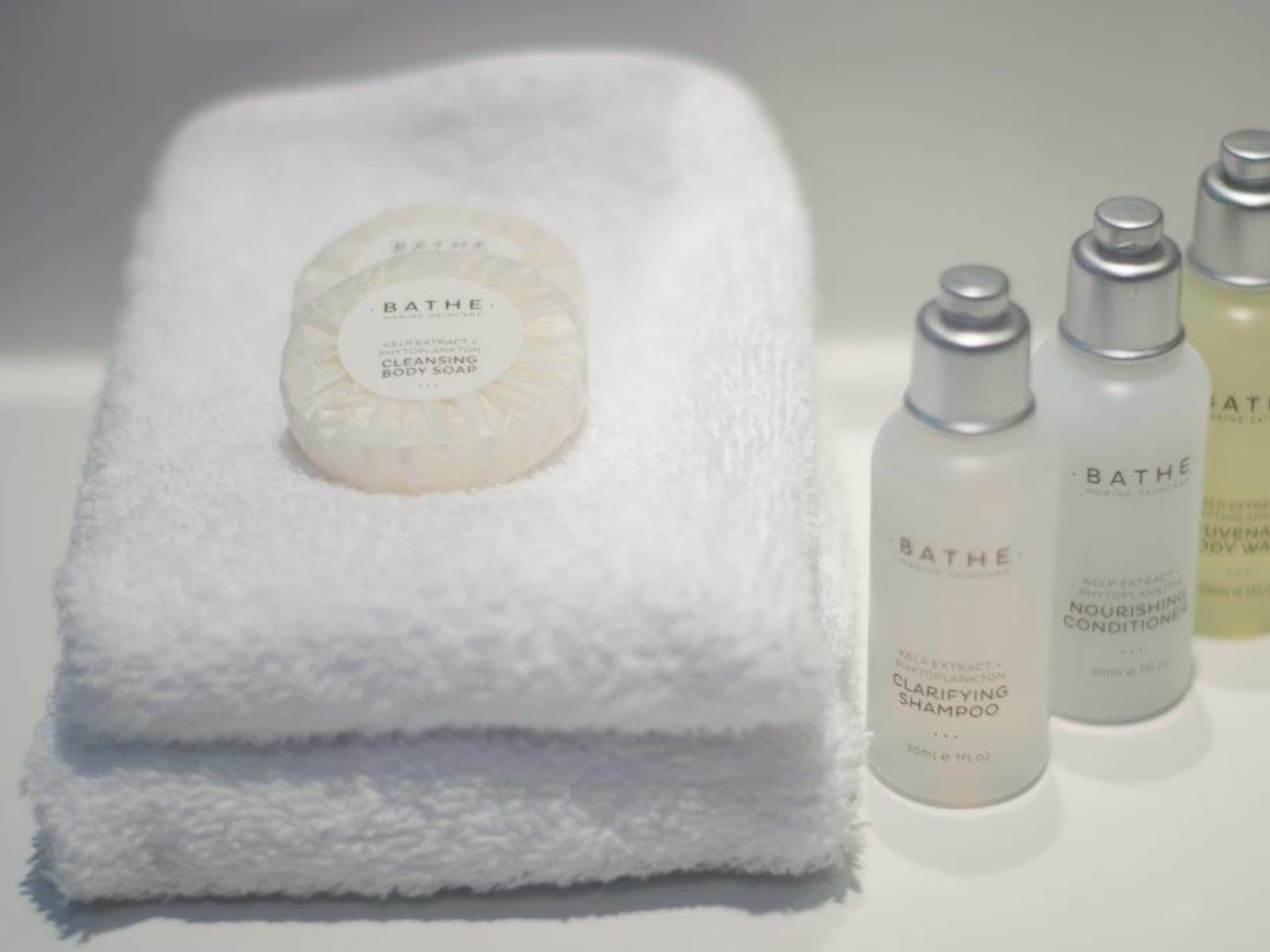 Una toalla blanca con una pastilla de jabón Bath & Body Works y tres botellas de Bath & Body Works.