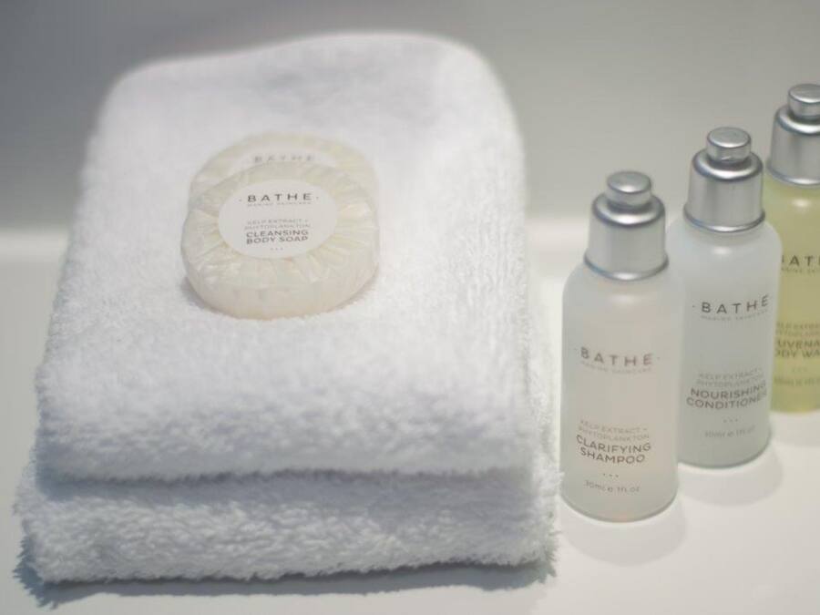 Una toalla blanca con una pastilla de jabón Bath & Body Works y tres botellas de Bath & Body Works.