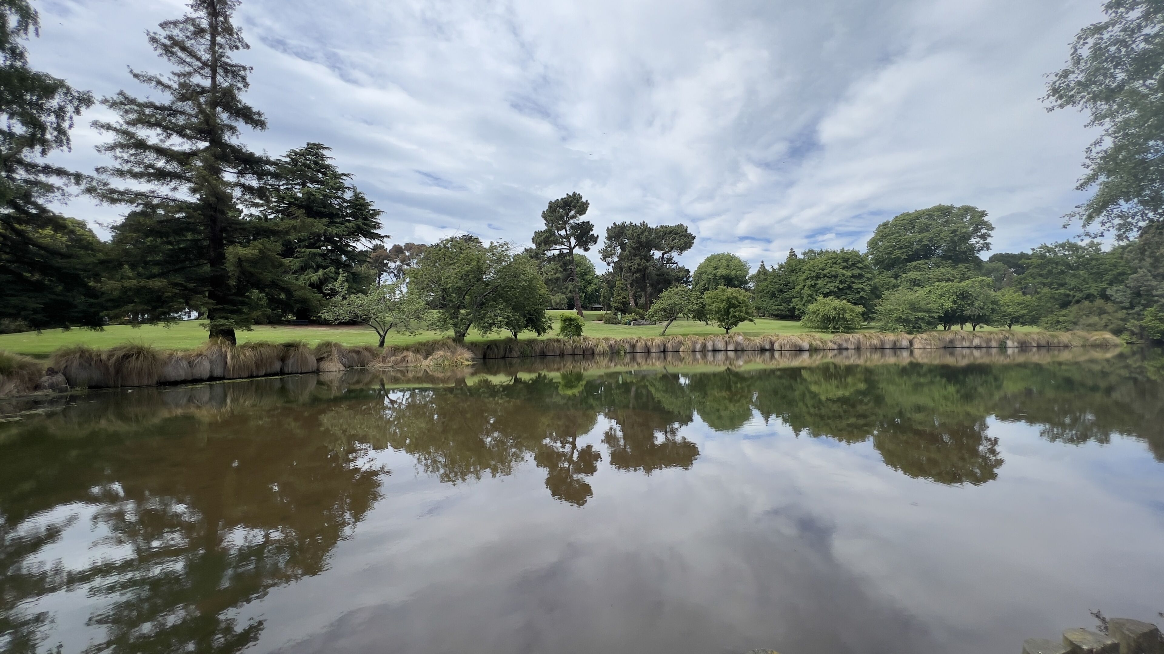 A tranquil lake with reflections of trees and a clear sky.