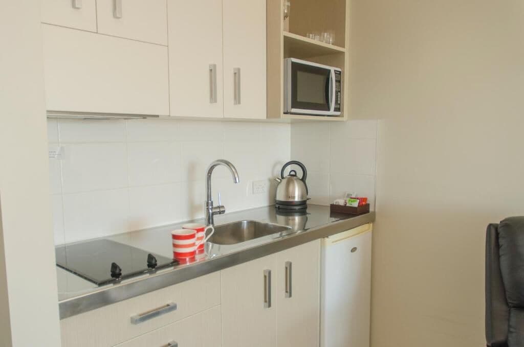 A compact kitchen with a microwave, kettle, and a sink.