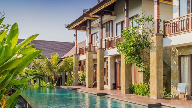 A resort with a swimming pool, multiple-story buildings, and lush greenery.