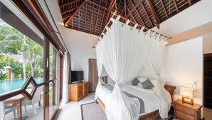 A bedroom with a four-poster bed, a television, and a nightstand with a lamp.