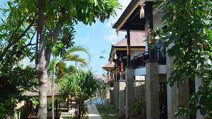 A traditional building with a tiled roof, surrounded by lush greenery and a clear sky.