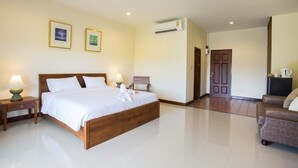 A hotel room with a wooden bed, two bedside tables with lamps, a flat-screen TV, and a door leading to another room. - Oh Amphawa Boutique Resort (Amphawa)