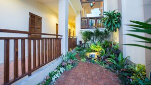 A corridor with a brick pathway, wooden railing, and lush greenery. - Oh Amphawa Boutique Resort (Amphawa)