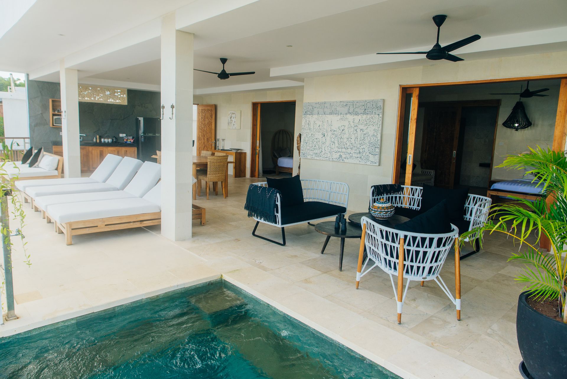 A poolside area with lounge chairs, a dining area, and ceiling fans.