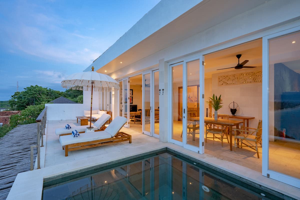 Une maison moderne dotée d’un patio entièrement vitré, d’une piscine et d’un coin repas avec des meubles en bois.