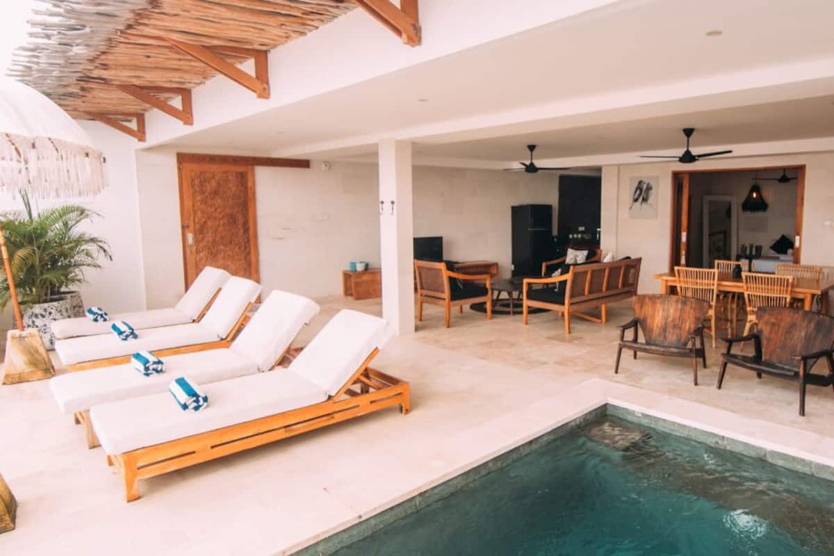Un espace piscine intérieur avec des chaises longues et une table à manger.