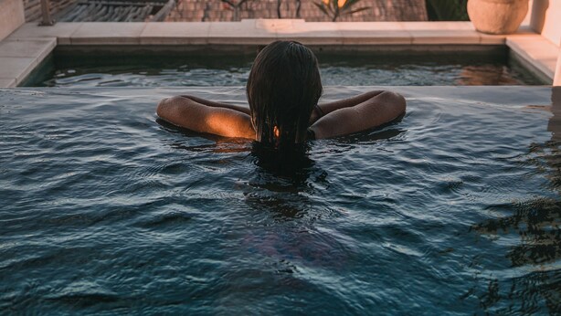 A person relaxing in a hot tub with a view of the ocean and boats. - Aqua Nusa - Boutique Lembongan Villas (Lembongan Island)