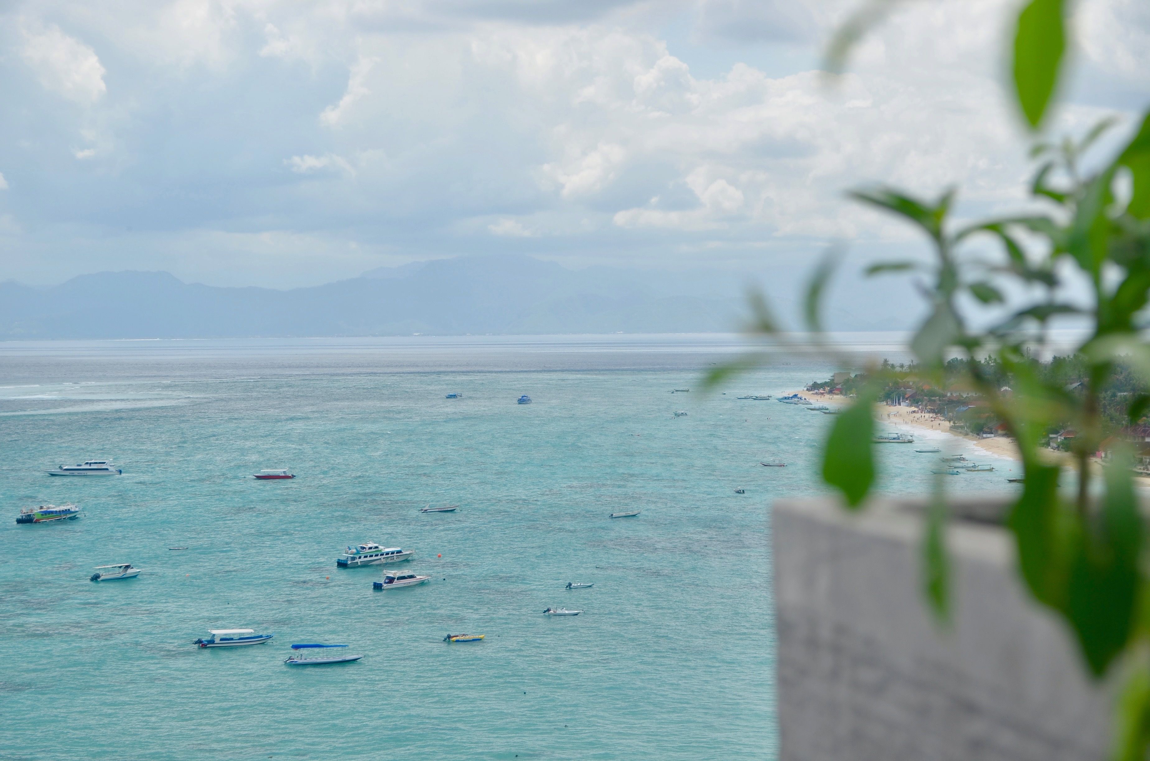 A coastal view with boats on the water and a beach in the distance.