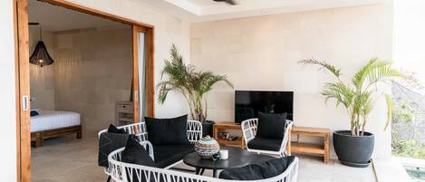 A modern living room with a sofa, chairs, a TV, and potted plants.