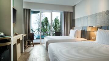 A hotel room with two beds, a desk, a chair, and a view of a swimming pool.
