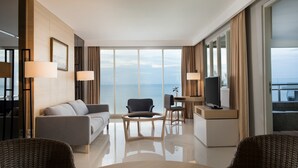Ein modernes Hotelzimmer mit einer Couch, Sesseln, einem Esstisch und einem Fernseher.