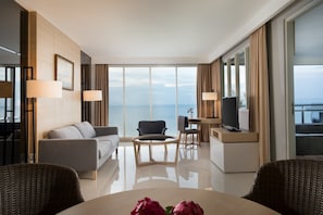 Una habitación de hotel moderna con sofá, sillones, una mesa de comedor y televisión.