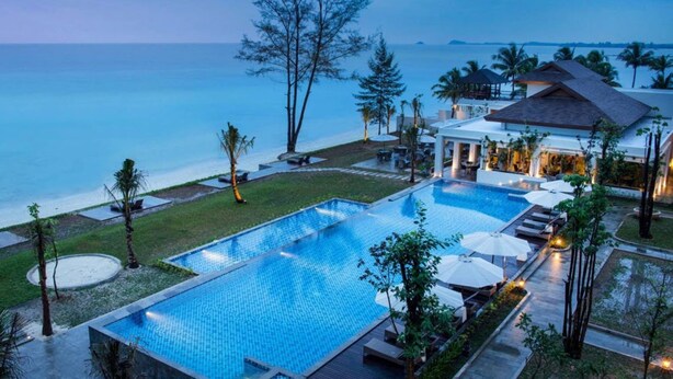 Ein Resort mit großem Pool, Liegebereichen und Meerblick.