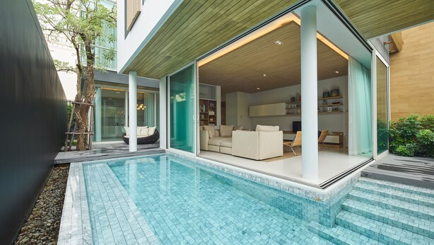 A modern house with a swimming pool, a glass door leading to a living room with a sofa and a TV, and a wooden ceiling. - Veranda Residence Pattaya Pool Villa (Pattaya)