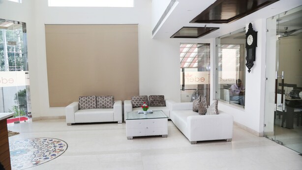 A modern living room with white sofas, a glass coffee table, and a large window.