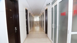 A hallway with doors on both sides, a tiled floor, and a ceiling with recessed lighting.