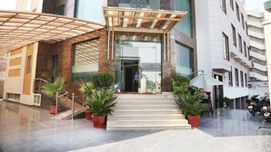 A hotel entrance with a covered walkway, potted plants, and a staircase leading to the entrance.
