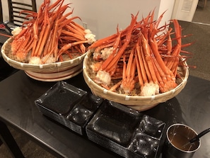 Zwei gewebte Körbe mit gekochten Krabbenbeinen auf einem Tisch.