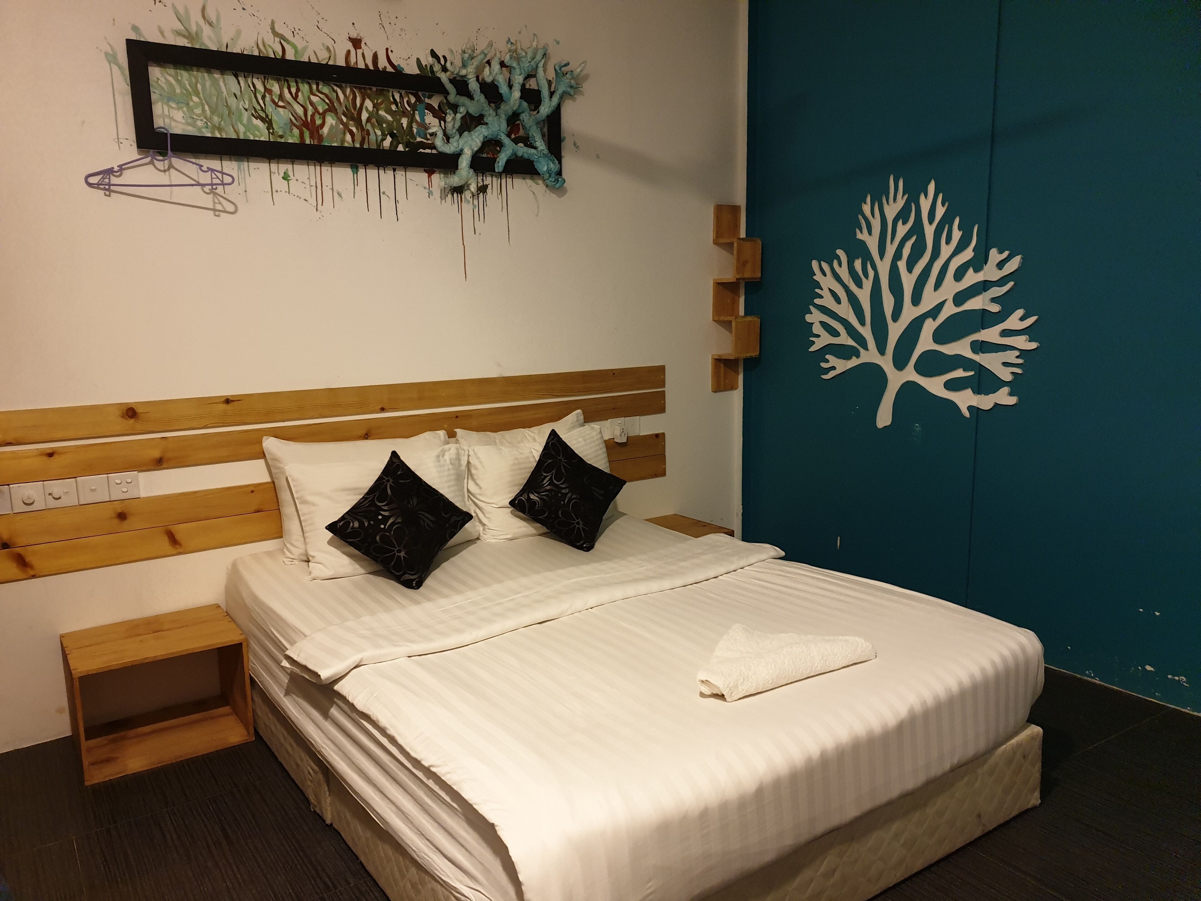 A neatly made bed with a wooden headboard, two black decorative pillows, and a white towel.