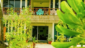 L'ingresso di un hotel con un balcone, piante in vaso e un cartello con su scritto "Seven Corals".