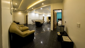 Una hall d'albergo moderna con un'area salotto, una reception e vista su un angolo dedicato alle camere.