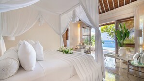 Ein Schlafzimmer mit Baldachinbett, Meerblick und einer Sitzecke mit Tisch und Stühlen.