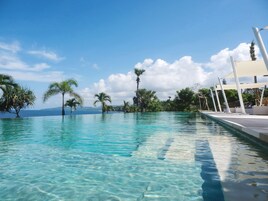 Una piscina cristalina con vista al océano y palmeras.