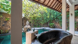 Ein Wellnessbereich mit Whirlpool, Steinwand und Schwimmbecken.
