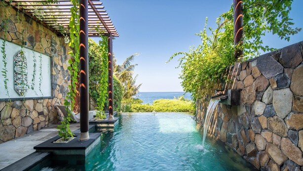 Ein Pool mit Steinverkleidung und Wasserfall, ein Pergola und Blick auf den Ozean.