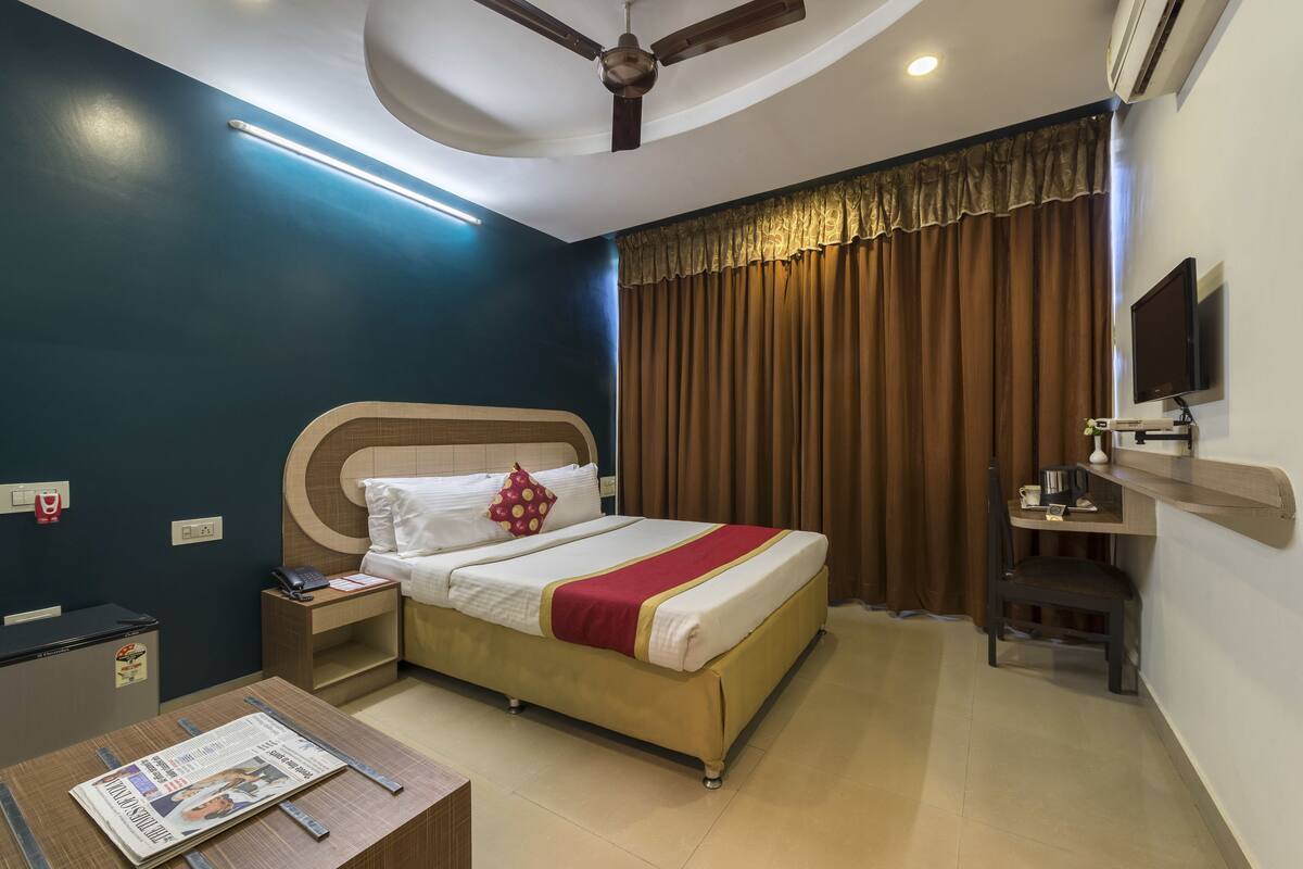Una habitación de hotel con cama, mesita de noche y escritorio con silla.
