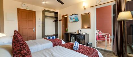 A hotel room with two beds, a ceiling fan, a TV, a desk, a chair, and an air conditioning unit.